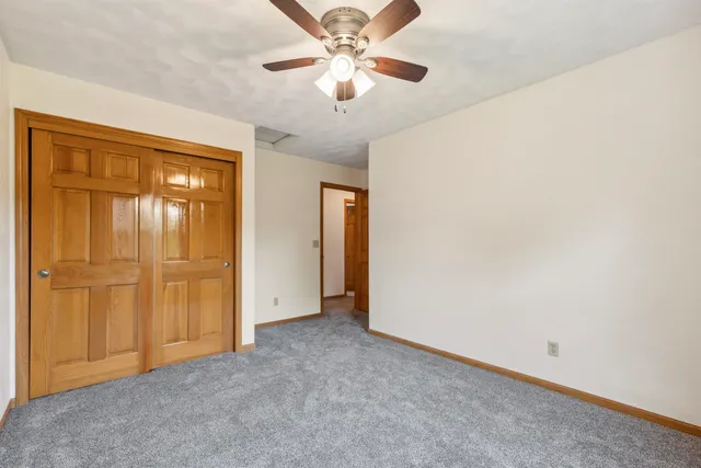 an empty room with closet and a chandelier fan