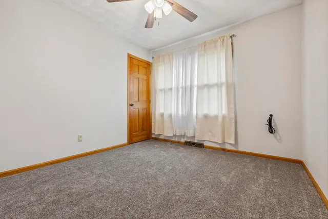 an empty room with a ceiling fan and window