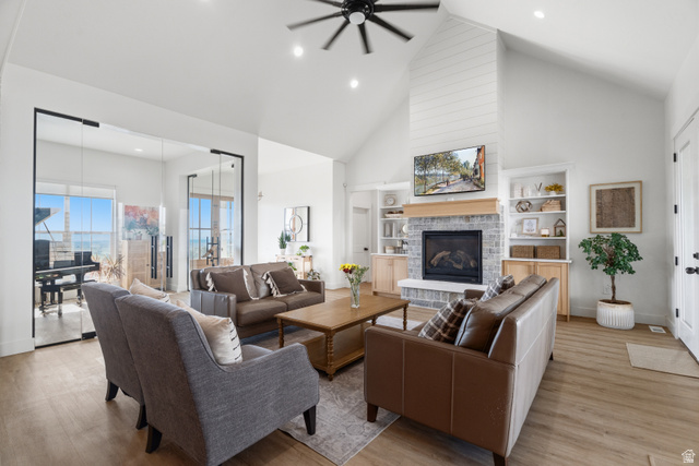 2013 South 100 West Perry, UT 84302 - Photo 10 of 49 Vaulted ceiling with a black ceiling fan, fireplace with a shiplap chimney and stone surround, wood-finish flooring, built-in shelving, and glass French doors leading to a separate room