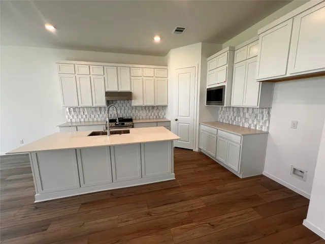 a kitchen with a sink cabinets and wooden floor