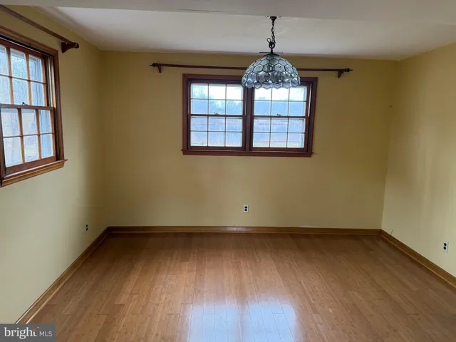 an empty room with wooden floor exposed radiator and windows