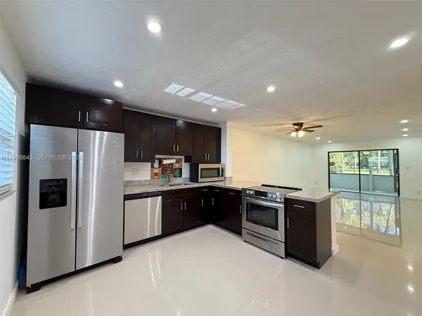 a kitchen with stainless steel appliances granite countertop a refrigerator a sink a stove and a refrigerator