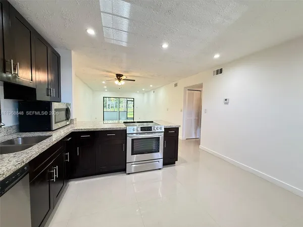 a large kitchen with stainless steel appliances granite countertop a stove a sink and a refrigerator