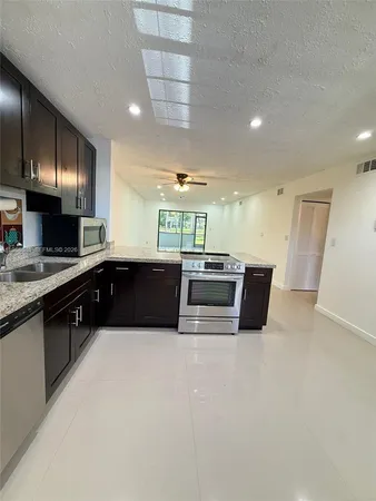 a large white kitchen with a large counter top and stainless steel appliances