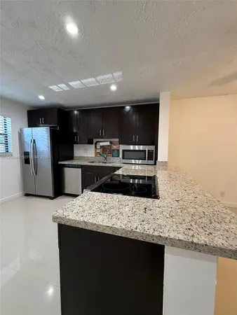 a kitchen with stainless steel appliances granite countertop a sink and a refrigerator