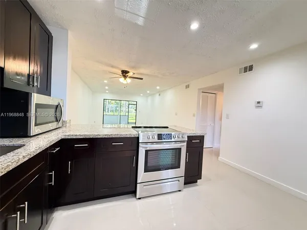 a kitchen with stainless steel appliances granite countertop a stove a sink and a microwave
