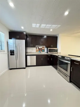 a large white kitchen with stainless steel appliances wooden cabinets and a stove