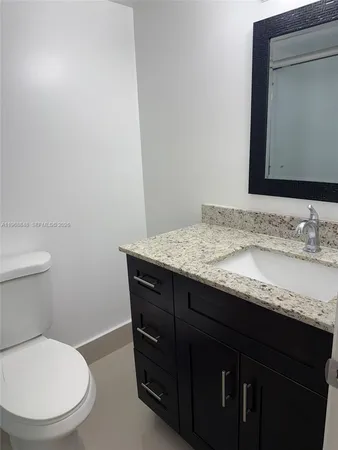 a bathroom with a granite countertop toilet sink and mirror