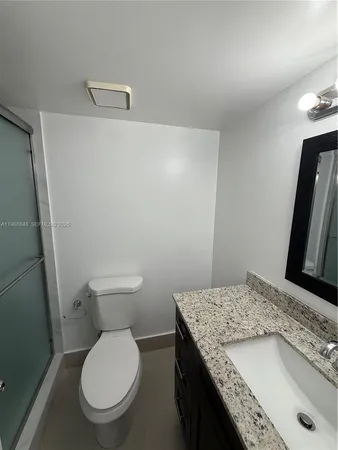 a bathroom with a granite countertop toilet and a sink
