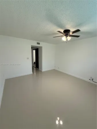 an empty room with a chandelier fan and a ceiling fan