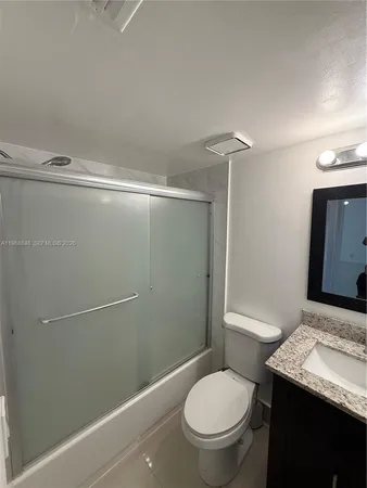a bathroom with a granite countertop sink toilet and shower