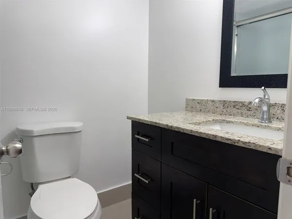 a bathroom with a granite countertop toilet sink and mirror