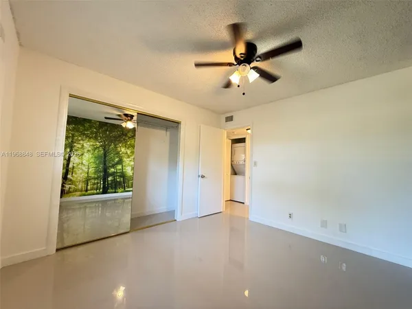 an empty room with a ceiling fan and a window