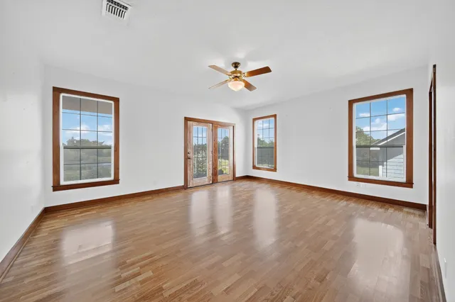 a view of an empty room with a window and wooden floor