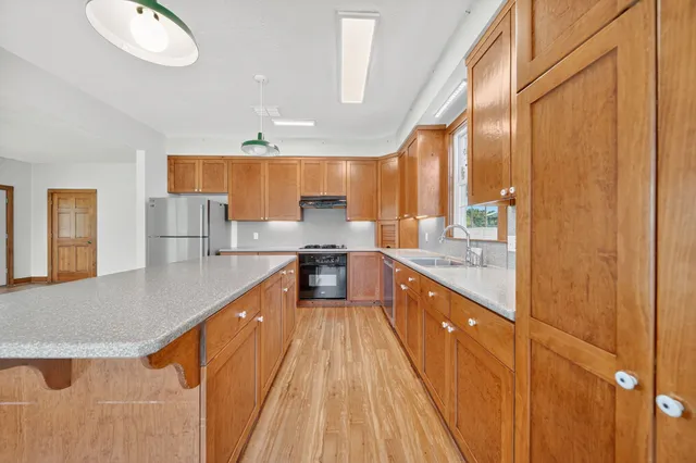 a large kitchen with stainless steel appliances granite countertop a sink and cabinets