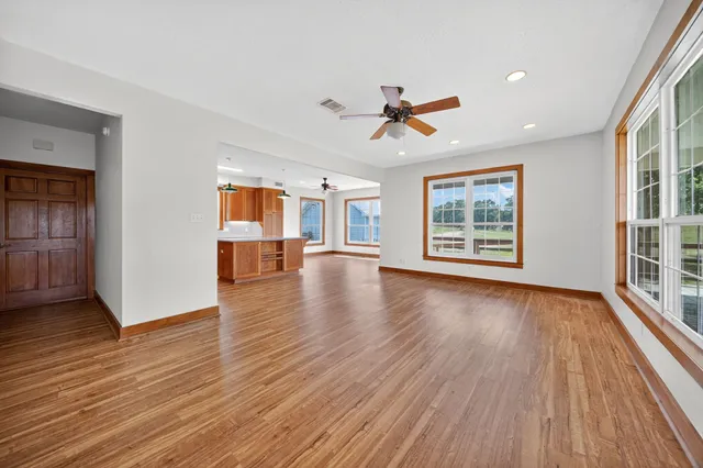 a view of an empty room with a window and wooden floor