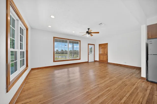 a view of an empty room with a window and wooden floor