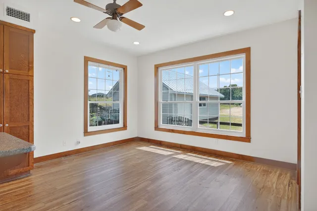 a view of an empty room with a window and wooden floor