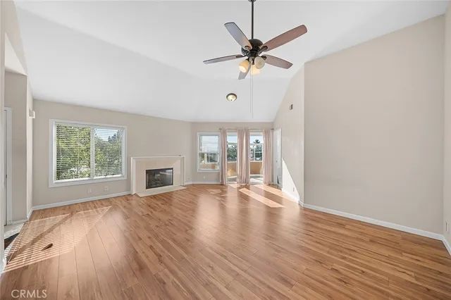 an empty room with wooden floor fan and windows