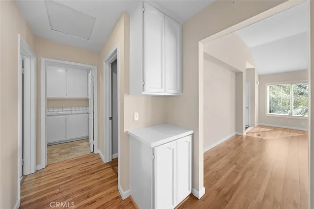 a view of a hallway with wooden floor and a bathroom