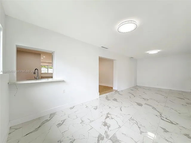 a view of a hallway with wooden floor and a living room