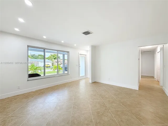 a view of empty room with kitchen and window