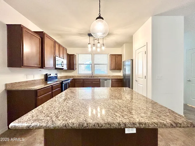 a large kitchen with kitchen island granite countertop a refrigerator a stove and a sink