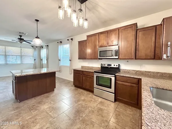 a kitchen with stainless steel appliances granite countertop a stove a sink and a microwave
