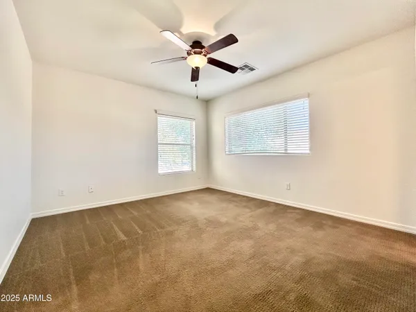 an empty room with windows and fan