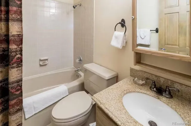 a bathroom with a granite countertop toilet sink and mirror