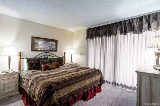 a bedroom with a bed a lamp and a large window