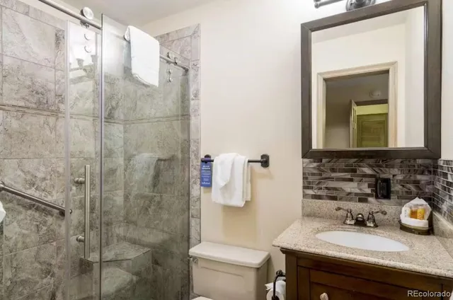 a bathroom with a granite countertop sink a toilet and shower