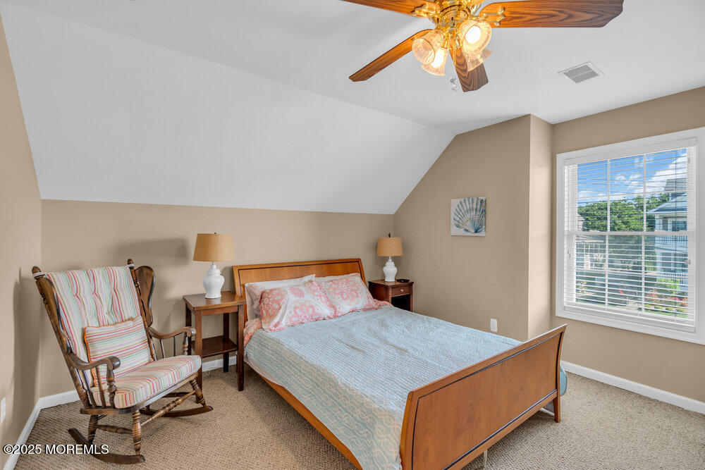 419 Central Avenue Spring Lake, NJ 07762 - Photo 27 of 41 a bedroom with a bed a chair and a chandelier