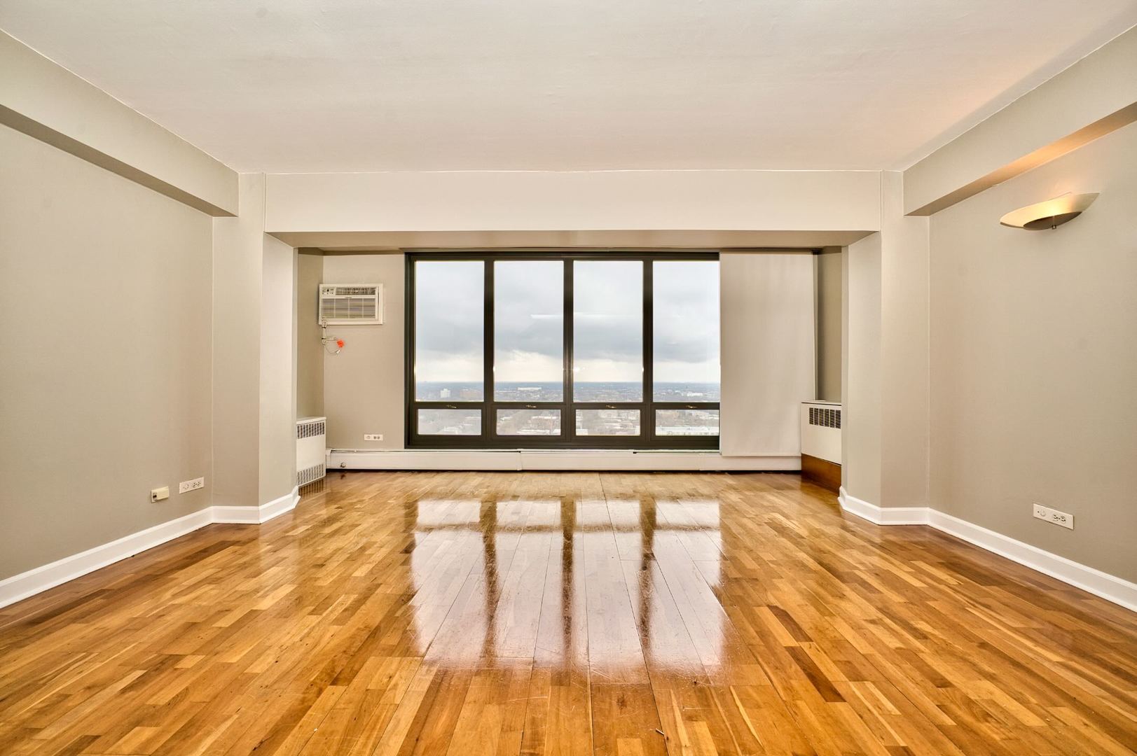 6166 North Sheridan Road, Unit 26A Chicago, IL 60660 - Photo 5 of 27 a view of an empty room with wooden floor and a window