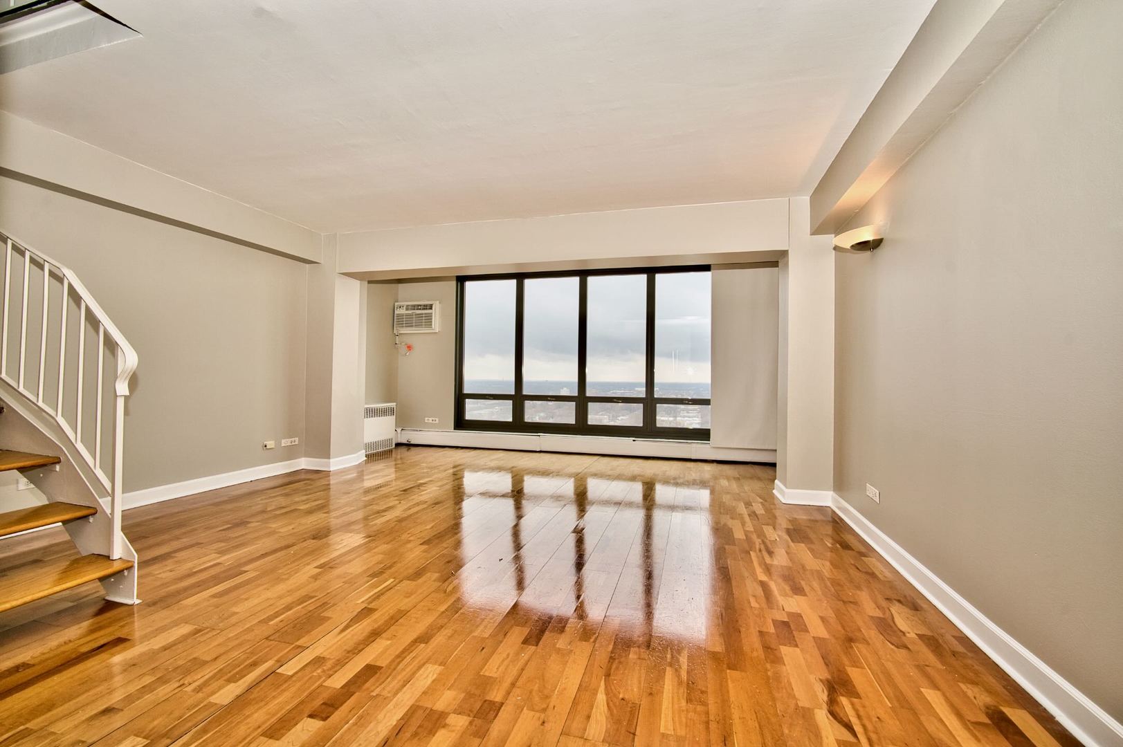 6166 North Sheridan Road, Unit 26A Chicago, IL 60660 - Photo 6 of 27 a view of an empty room with wooden floor and a window