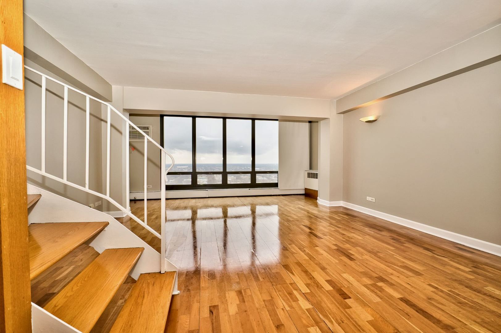 6166 North Sheridan Road, Unit 26A Chicago, IL 60660 - Photo 7 of 27 a view of an empty room with wooden floor and a window