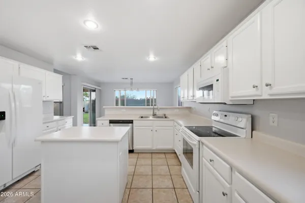 a kitchen with a sink a stove a refrigerator and white cabinets