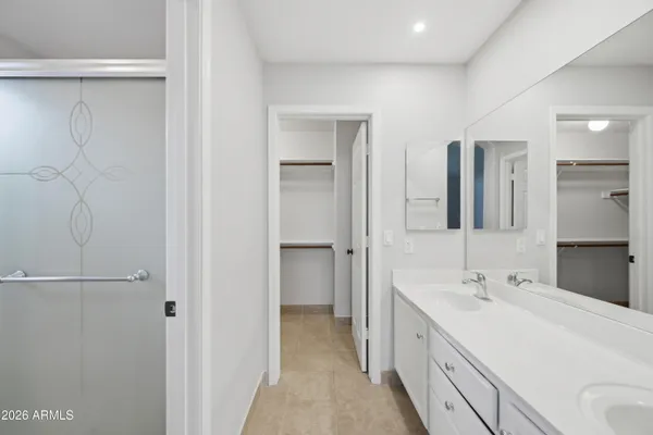 a spacious bathroom with a double vanity sink a mirror and a shower