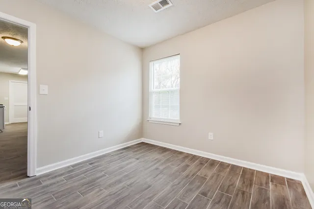 an empty room with wooden floor and windows