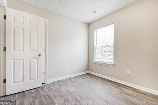 an empty room with wooden floor and windows