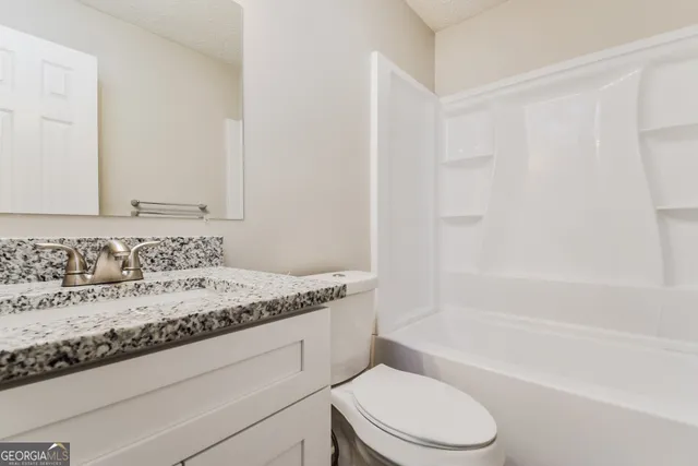 a bathroom with a granite countertop sink toilet and shower