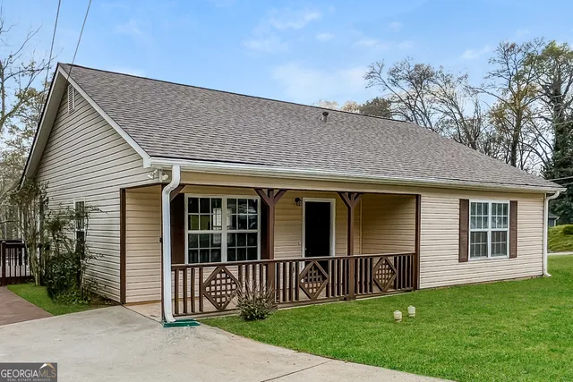 a view of a house with a yard and large tree