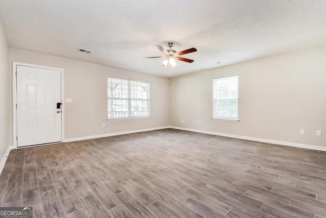an empty room with windows and ceiling fan