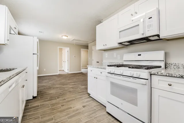 a kitchen with granite countertop white cabinets and white appliances