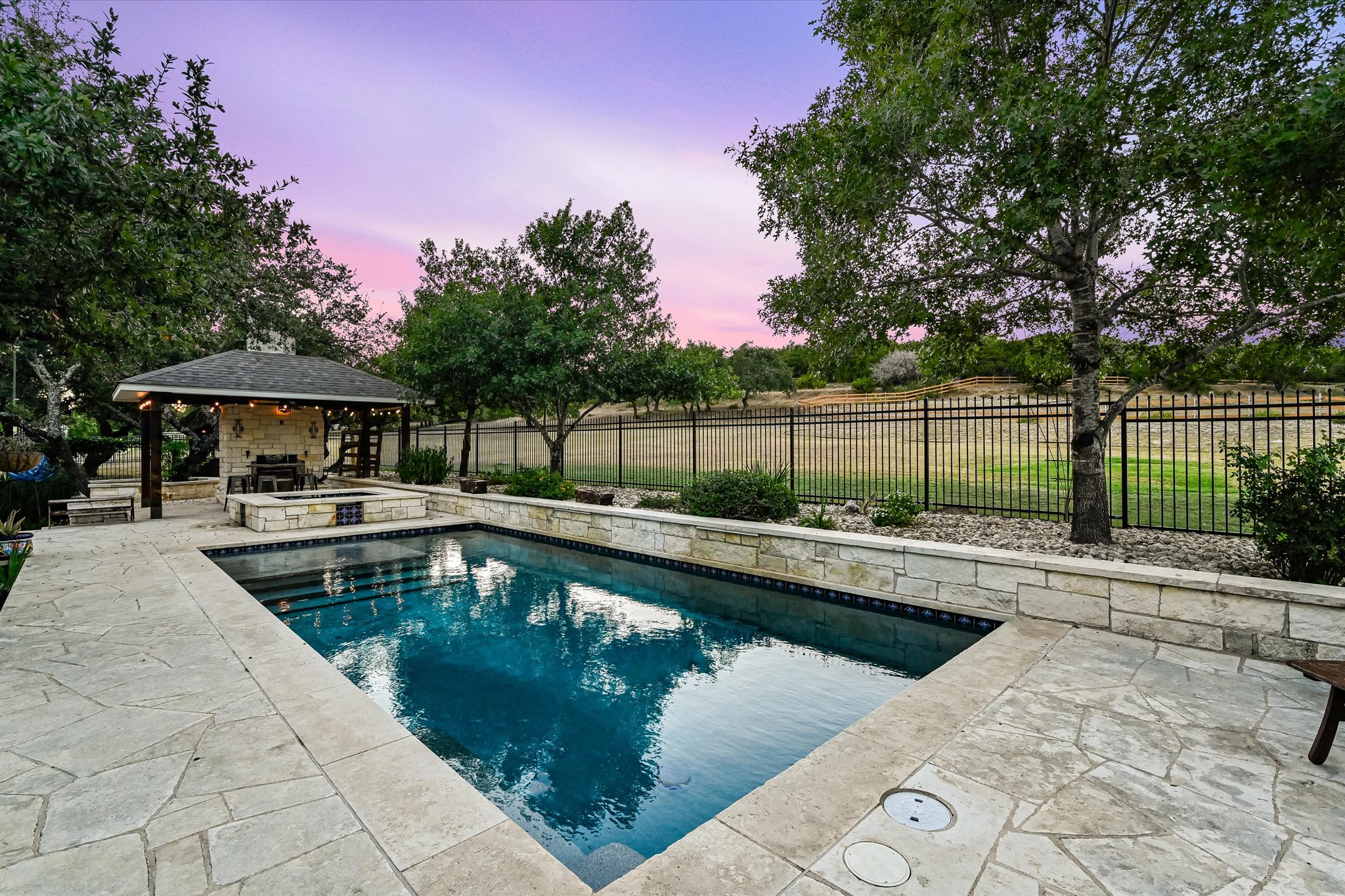 786 Ranchers Club Lane Driftwood, TX 78619 - Photo 27 of 33 Pool at dusk featuring a fenced backyard, a patio area, and a pool with connected hot tub