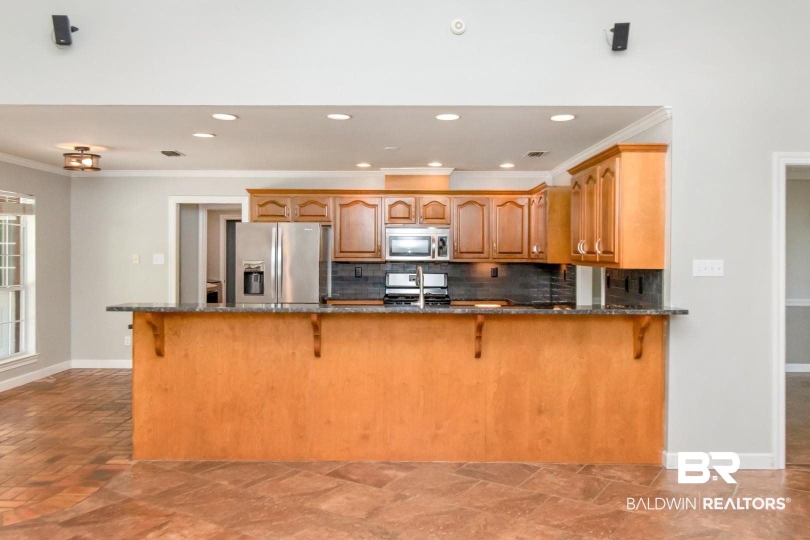 10691 Hunters Ridge Drive Mobile, AL 36695 - Photo 10 of 37 Kitchen featuring wood cabinetry, stainless steel appliances, a dark backsplash, and a breakfast bar with stone-finish countertops