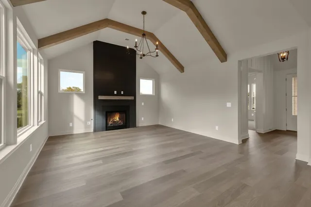 a view of an empty room with wooden floor fireplace and a windows