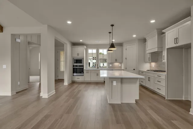 a kitchen with stainless steel appliances kitchen island wooden floors wooden cabinets and entryway