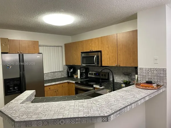 a kitchen with granite countertop a sink a stove top oven a refrigerator and a sink