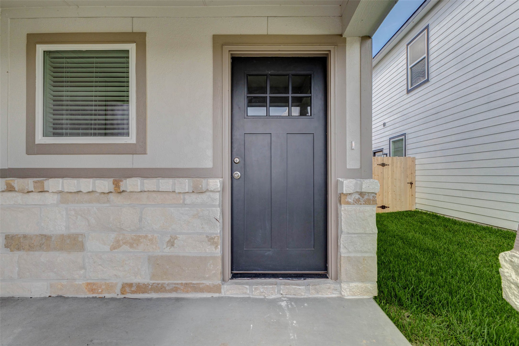 6467 Escondido Drive Rosharon, TX 77583 - Photo 8 of 32 Covered front entry with stone accents, a dark front door, adjacent window, and protected porch area. This close-up highlights the home’s inviting threshold, neutral exterior finishes, and convenient side-yard access with privacy fencing just beyond the entry.